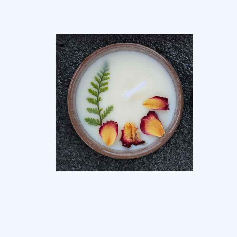 ドライフラワーと香りのよいキャンドルが入った陶器のカップ